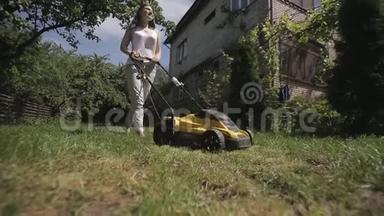 女孩正赤脚用黄色的割草机修剪一块<strong>凹凸</strong>不平的草坪